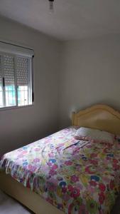 南卡希亞斯的住宿－Recanto do Descanso，一间卧室配有一张带五颜六色的被子的床和窗户