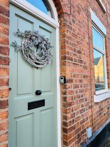 a door to a brick building with a wreath on it at NEW Overleigh Cottage, with optional Hot tub in Chester
