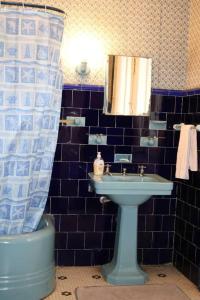 a blue tiled bathroom with a sink and a shower curtain at Casa Histórica en Boyacá in Sogamoso
