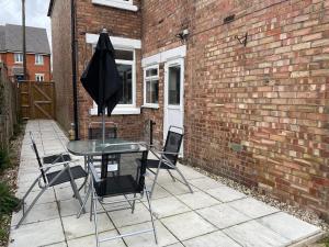 um pátio com uma mesa, cadeiras e um guarda-sol em Sunbeam cottage contractor Parking WiFi Garden em Colchester