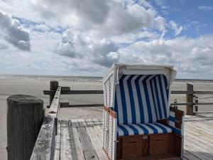 ein blauer und weißer Stuhl auf einem hölzernen Pier in der Unterkunft Luv & Lee - Meerblick 34 in Sankt Peter-Ording