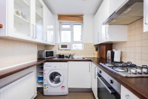 a white kitchen with a washing machine in it at Comfortable 2 Bedroom in Marylebone in London