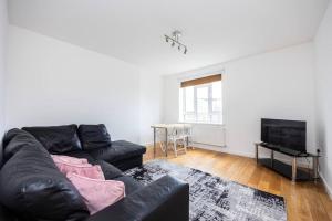 a living room with a black leather couch and a television at Comfortable 2 Bedroom in Marylebone in London