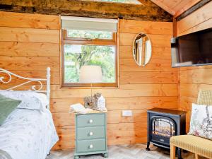 a bedroom with wooden walls and a bed and a fireplace at 1 Bed in Bridport 93355 in Marshwood