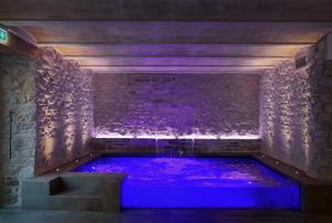 - un bain à remous dans une pièce avec éclairage violet dans l'établissement Monastero Sant'Alberico Relais, à Balze