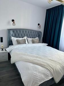 a bedroom with a large bed with blue curtains at Evelyn Apartment in Bistriţa