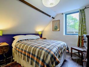 a bedroom with a bed with a plaid blanket and a window at 3 Bed in Capel-y-Ffin 93362 