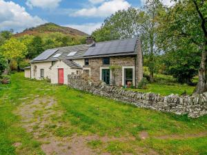a stone house with a red door and a stone wall at 3 Bed in Capel-y-Ffin 93362 