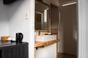 La salle de bains est pourvue d'un lavabo et d'un miroir. dans l'établissement Hôtel Le Tivoli, à Sisteron