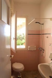 a bathroom with a toilet and a window and a sink at Sunny summer house with sea view in Koropíon