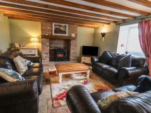 a living room with leather furniture and a fireplace at The Barn in Saltburn-by-the-Sea