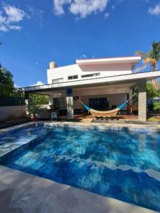a swimming pool with a hammock in front of a house at Casa Kamima near playa Conchal! in Brasilito