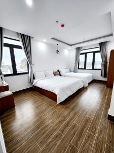 um quarto com 2 camas e pisos em madeira em Happy Bun Hotel Da Lat em Da Lat