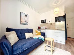a living room with a blue couch and a kitchen at L'évasion Marine à la plage 2P in Houlgate