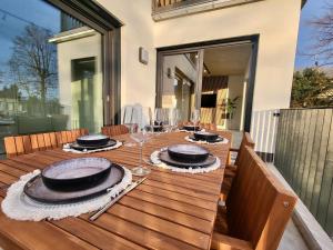 a wooden table with plates and wine glasses on it at SiOUX: stilvolles Designapartment am Bodensee in Lindau-Bodolz