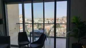 a room with a large window with chairs and a table at Brand New 3 Bedroom Apartment in Shalem Tower in Jerusalem