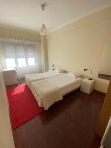 a bedroom with a large white bed and a red rug at Casa Encantada - Benfica in Lisbon