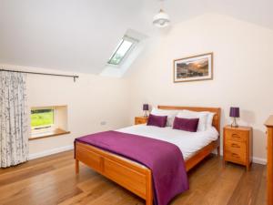 um quarto com uma cama com um cobertor roxo em 3 Bed in Askham 93429 em Askham