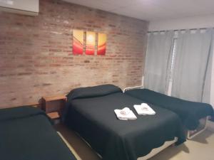 sypialnia z 2 łóżkami i ceglaną ścianą w obiekcie LOS Teros dptos w mieście Villa María