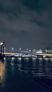 Shadwell - walking distance to Tower Bridge, two stations in close proximity في لندن: جسر فوق هيئة ماء في الليل