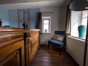 a room with a wooden dresser and a blue chair at Hotel Burg Abenberg in Abenberg