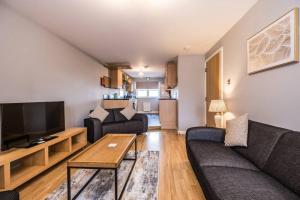 a living room with a couch and a tv at Union Square modern 2 bedroom apartment in Aberdeen
