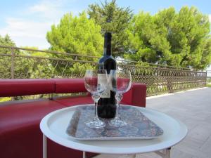 a bottle of wine sitting on a table with two glasses at Villa Il Giovane Alloro in Martina Franca