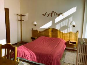 サン・ピエール・ド・シャルトルーズにあるHotel Victoriaのベッドルーム1室(木製ベッド1台、赤い毛布付)