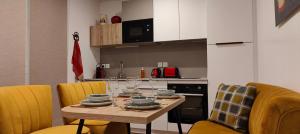 的住宿－Aux Sons des Cloches - Chalet avec Jacuzzi, Sauna et vue panoramique，餐桌、黄色椅子和厨房
