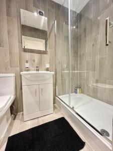 een badkamer met een bad, een wastafel en een douche bij Stunning Terrace Apartment - City Centre & Next to Tube Station in Ealing