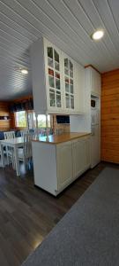 una cucina con armadi bianchi, tavolo e sedie di Hallan Alpit A mökki a Hyrynsalmi