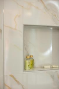 a shelf in a bathroom with two bottles on it at Swan House - Panoramic View in Kommeno in Kommeno
