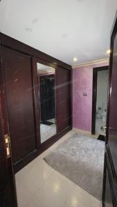 een kamer met paarse muren en een badkamer met een spiegel bij Tarawneh & Thawabi in Amman