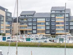 un grand bâtiment avec des bateaux amarrés dans un port de plaisance dans l'établissement Appartement T2 avec parking à Courseulles-sur-Mer - FR-1-746-10, à Courseulles-sur-Mer