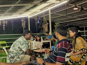 um grupo de pessoas sentadas à volta de uma mesa em Mitra Hostel (By The Pool) em Vagator