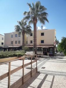 een resort met palmbomen en tafels en een gebouw bij Vilamoura 2 bed new apartment in Vilamoura