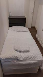 een groot bed met witte lakens en een houten hoofdeinde bij Bethnal Green Guest House in Londen