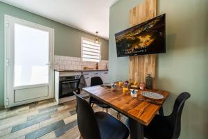 Una cocina con una mesa de madera con sillas y un televisor. en Le Grand Colibri, en Saint-Denis