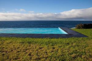 a swimming pool with the ocean in the background at Casa Azul in Lajes do Pico