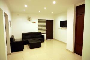 a living room with a black couch and a television at GRANDE IVORY INN in Kalpetta