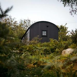 a black building in the middle of a field at The Deerstone Luxury Eco Hideaway in Laragh