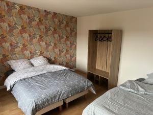 1 dormitorio con cama y papel pintado con motivos florales en Jolie petite maison 4-6 couchages, en Auchy-les-Mines