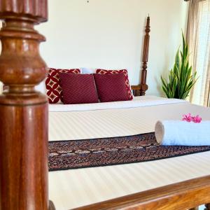 1 cama con almohadas rojas y marco de madera en Santa Maria, Trivandrum - An Airport Boutique by the Sea en Thiruvananthapuram