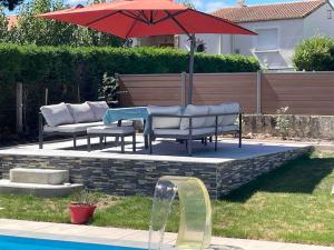 a table and chairs and an umbrella next to a pool at Charmant T1 privé avec vue et accès piscine in Basse-Goulaine