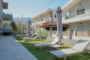 a row of lounge chairs with umbrellas in front of a building at Oli Terra in Skala Potamias