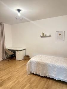 a white bedroom with a bed and a desk at FMI Apartmets next to Frankfurt Airport in Frankfurt/Main