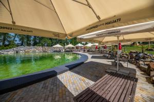 a swimming pool with chairs and umbrellas next to a swimming pool at Hotel Allvet in Drnovice