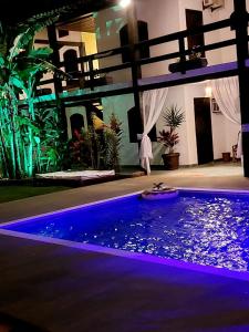 a swimming pool with purple lights in a house at Pousada Solar de Itaúna in Saquarema