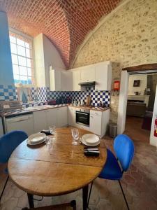 uma cozinha com uma mesa de madeira e cadeiras azuis em Cozy flat in castle near Fontainebleau - 10 min em Fleury-en-Bière