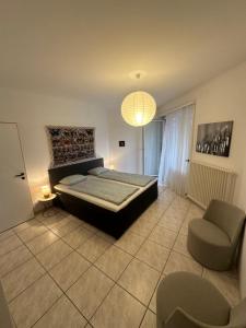 1 dormitorio con 1 cama, 1 silla y 1 lámpara de araña en Lungolago Blu Sky en Locarno